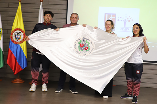Juan José Giraldo Montoya, del equipo de Natación de la Sede y Lina Morales, integrante de Salsa UNAL, recibieron la bandera. Foto Unimedios.